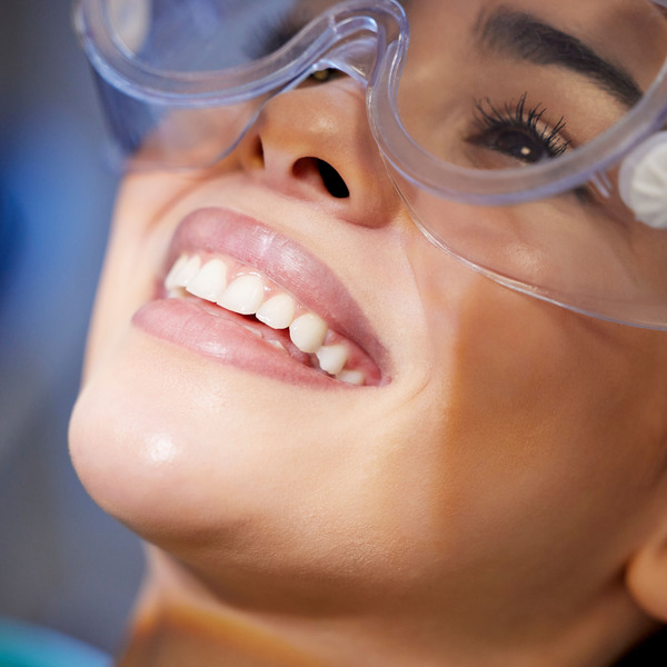 Face, goggles and smile with woman at dentist for oral hygiene or dental care appointment closeup. Checkup, healthcare and medical with happy patient in chair at clinic for mouth cleaning or exam